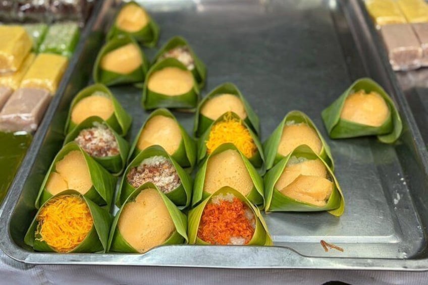 A tray of food items wrapped in leaves, including some with visible toppings. 4