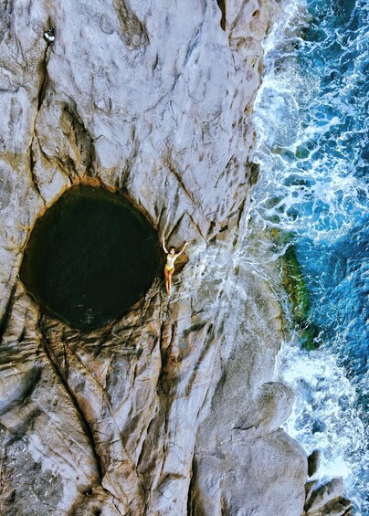 A person standing on a rocky cliff by the sea. 2