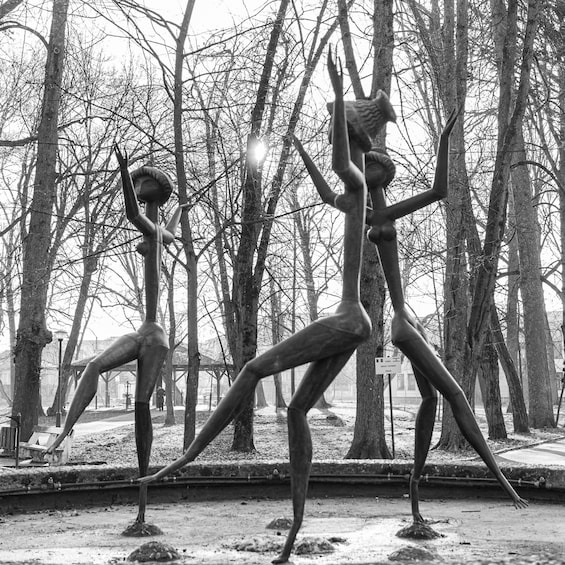 A sculpture of a human figure in a dynamic pose, set against a backdrop of leafless trees and a clear sky. 5