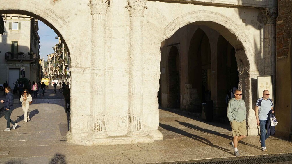 An ancient stone archway with people walking through it. 3
