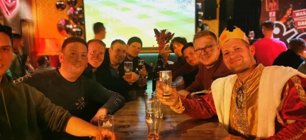 A group of people sitting at a table in a bar, holding drinks. 5
