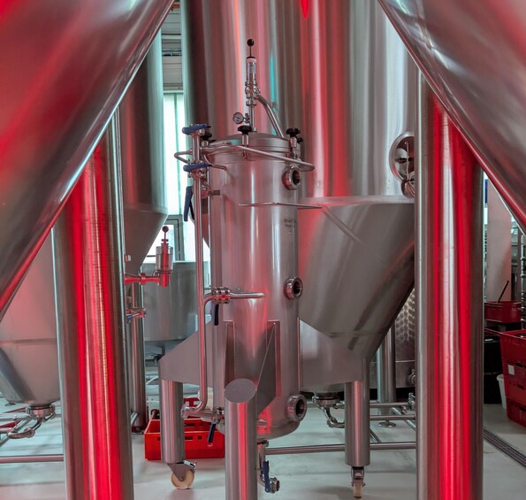 A stainless steel industrial brewing setup with tanks, pipes, and valves. 3