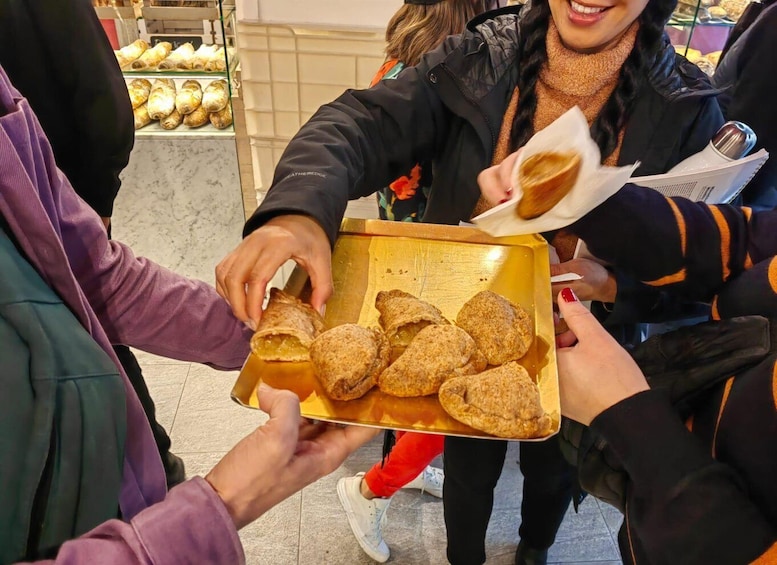 A person holding a tray with several pastries. 5