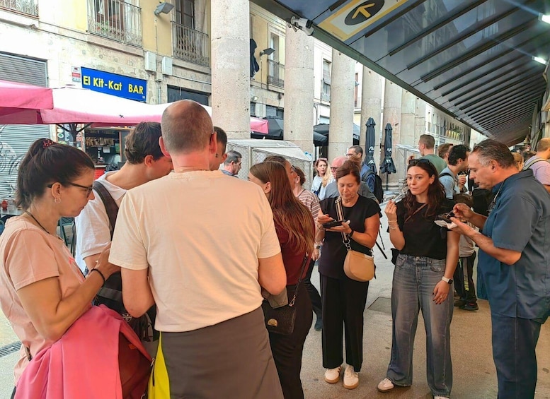 A busy outdoor market with people shopping and standing around. 4