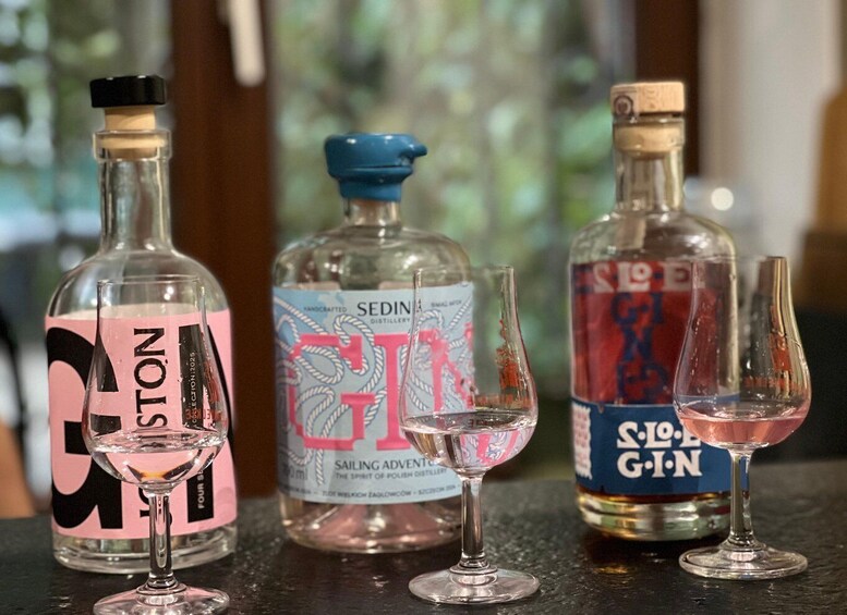 Three bottles of gin and two empty glasses on a bar counter. 1