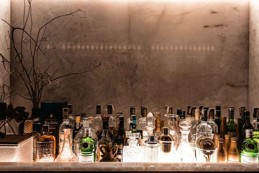 A bar counter with various bottles of liquor and a potted plant. 5