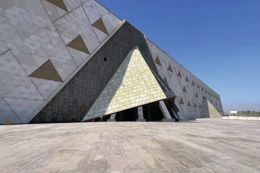 A large, modern building with a unique geometric design, featuring a prominent triangular section and patterned facade. 2