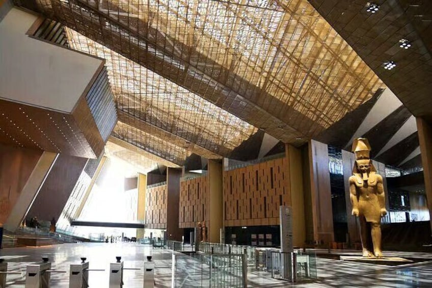 A modern interior with a large golden statue, geometric patterned walls, and a unique ceiling design. 5