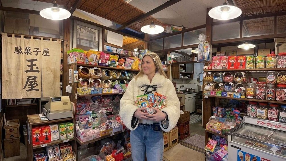 A person holding a variety of colorful items in a store with wooden shelves and a sign in Japanese. 1