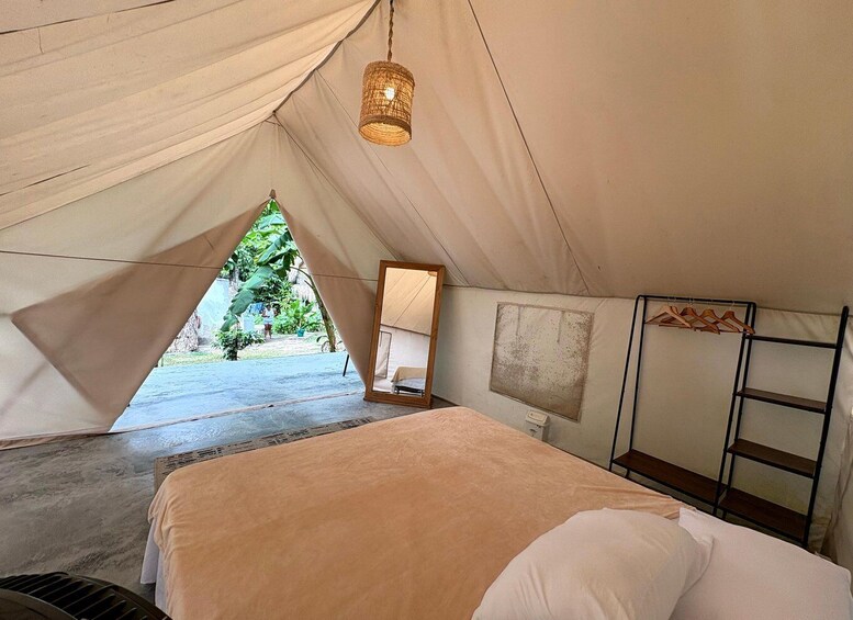 A tent with a bed, a hanging light, and a ladder. 3