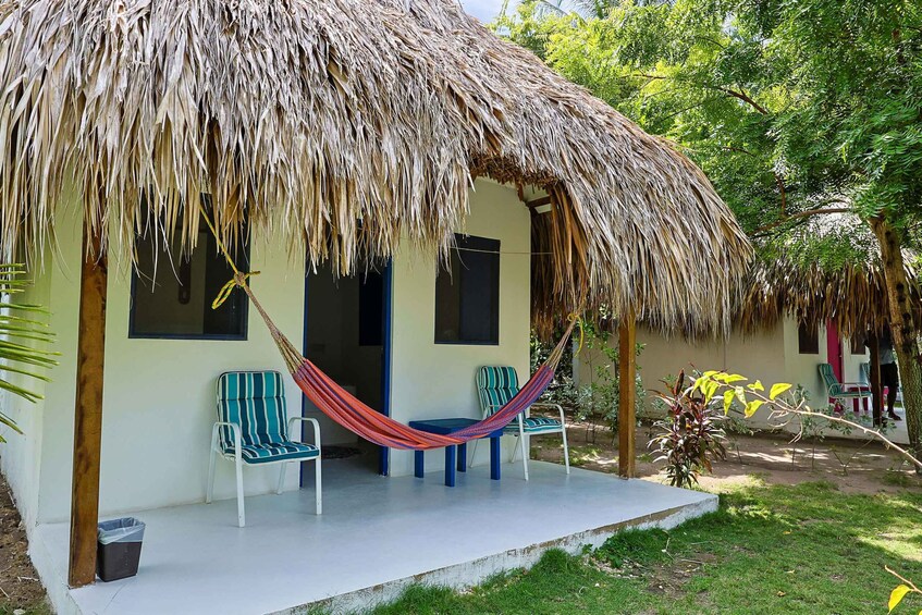 A thatched-roof house with two chairs and a hammock. 5