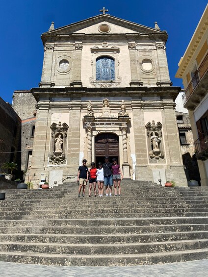 A historic church with a bell tower, a large arched entrance, and a statue on the facade. 1
