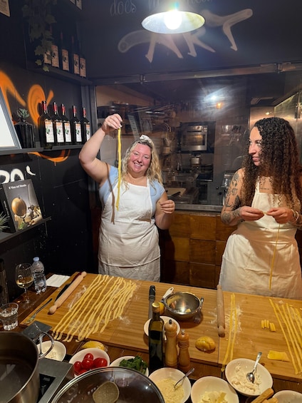 Deux personnes dans une cuisine, en train de préparer des pâtes, avec les ingrédients et les ustensiles de cuisine disposés sur le plan de travail. 4