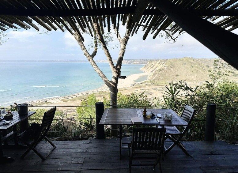 A wooden deck overlooking a beach with a view of the ocean and distant hills. 1