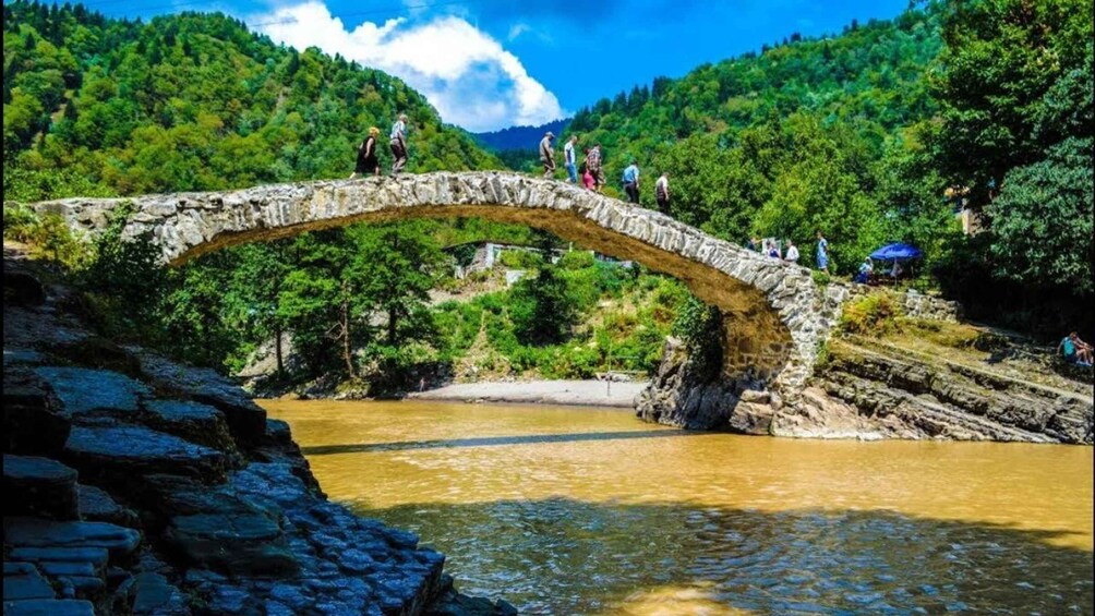 A stone bridge over a river with people walking on it. 2