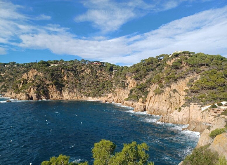 A coastal landscape with cliffs, a clear blue sea, and scattered buildings. 3