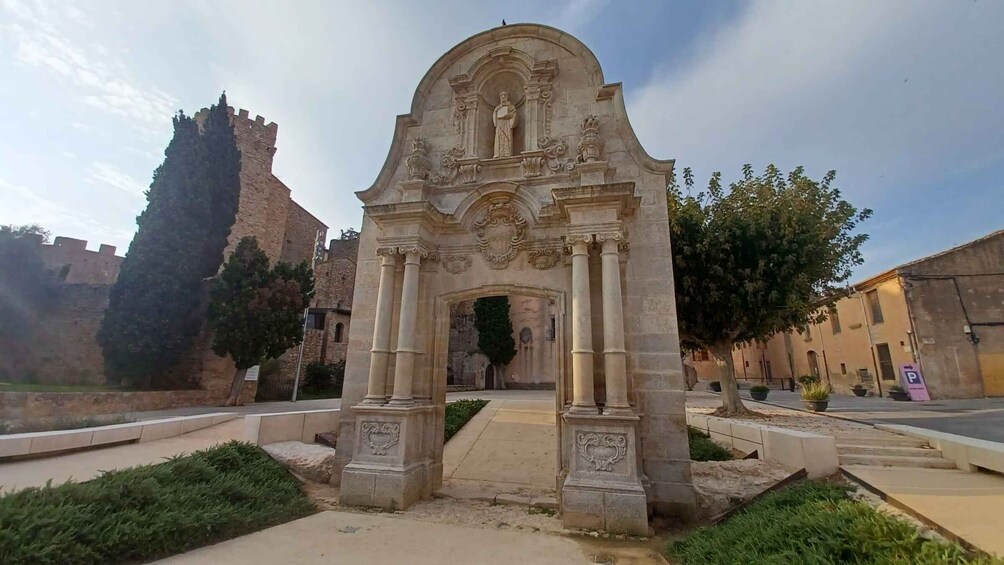 An ornate stone archway with a statue, a historic building, and a castle in the background. 5