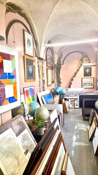 An art gallery with framed paintings, globes, and a map on display. 4
