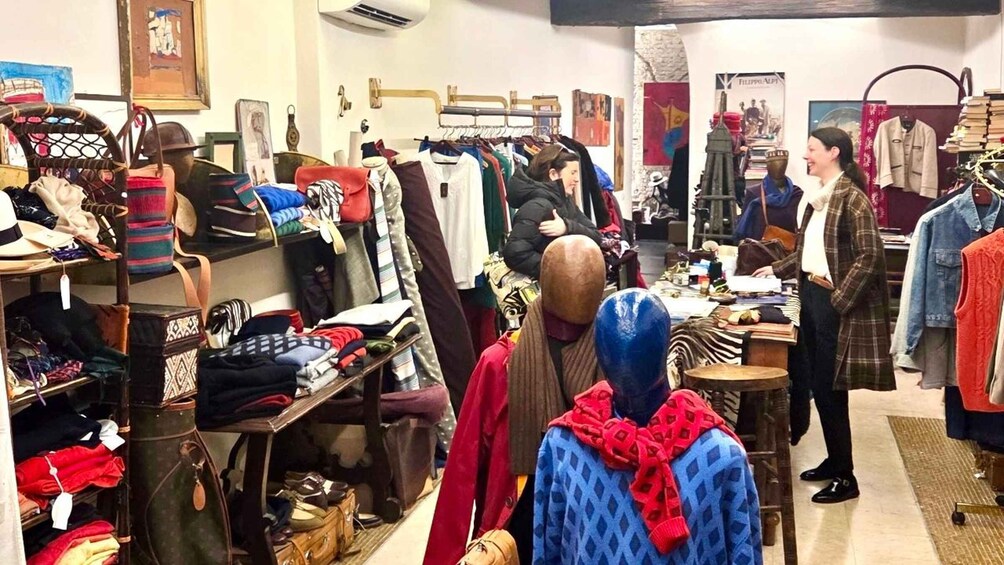 A clothing store with racks of clothes and a table with items on display. 2