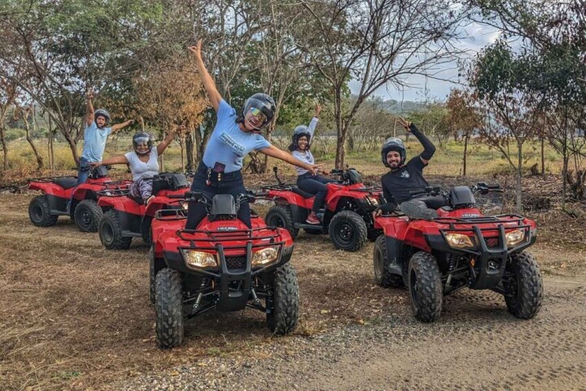 A group of people on red ATVs in a rural setting with trees and open land. 5