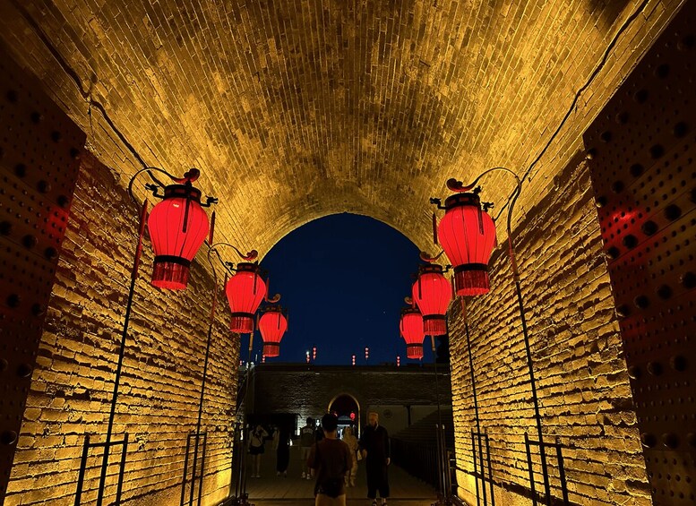 A brick tunnel with red lanterns and a dark sky above. 2
