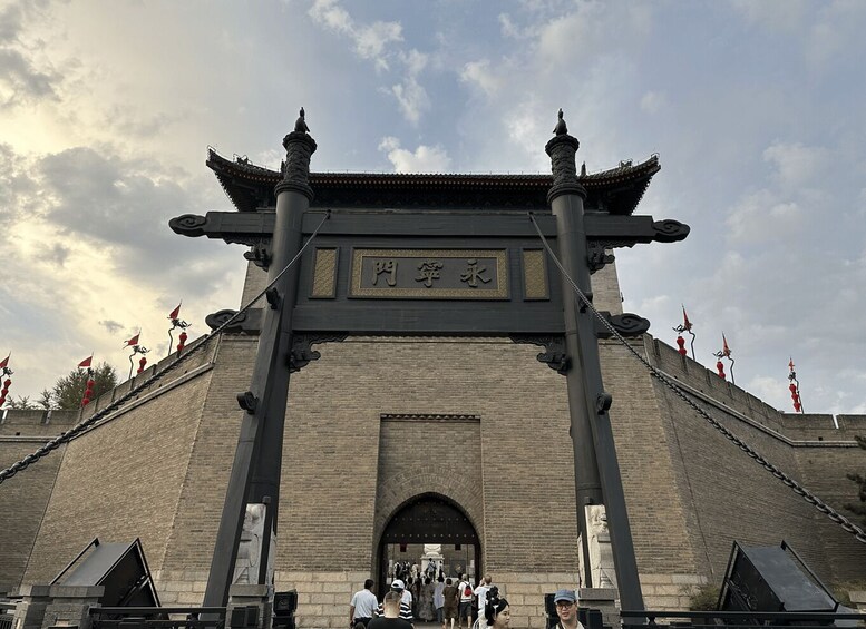 A traditional Chinese gate with inscriptions, flanked by stone lions and red flags. 3