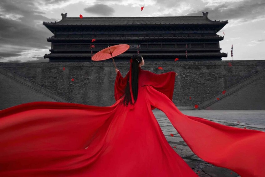 A person in a flowing red garment with an umbrella, standing in front of a traditional Chinese gate. 4