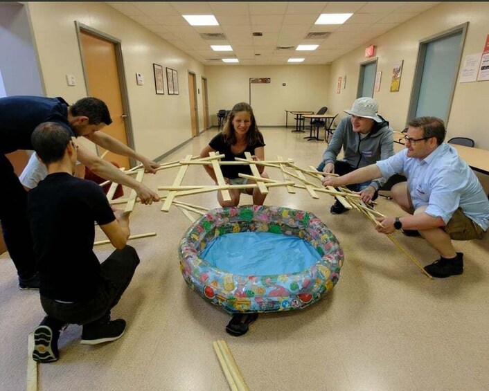 A group of people playing a game involving a pool table and wooden sticks. 5
