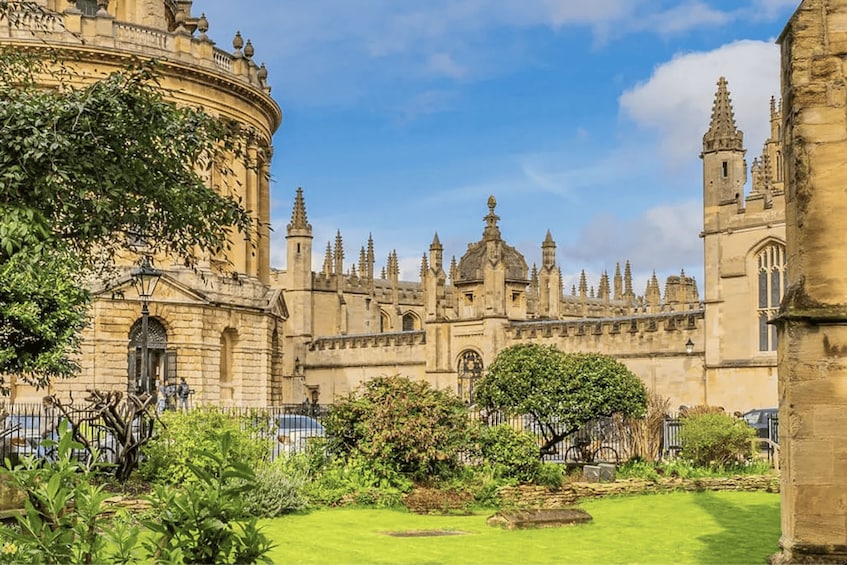 A historic building with intricate architecture, a well-maintained garden, and a clear blue sky. 4