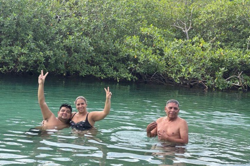 Three people in a body of water surrounded by dense green foliage. 2