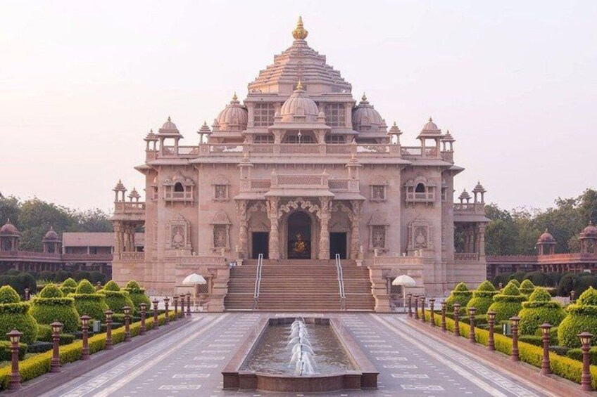 A large, ornate temple with multiple domes and intricate carvings, surrounded by well-manicured gardens and a central water feature. 2