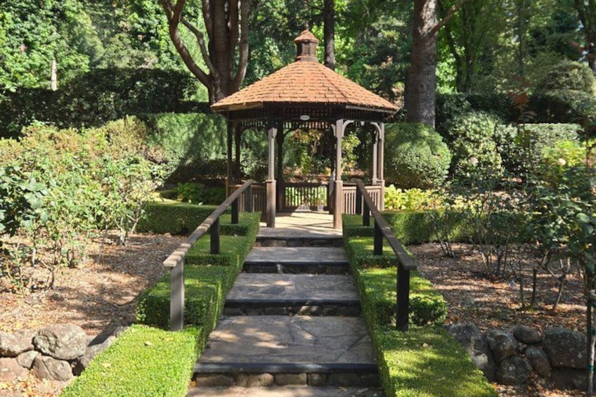 A stone pathway leading to a gazebo in a well-maintained garden. 4