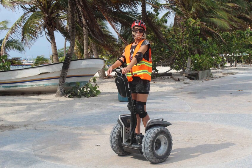 Henkilö ajaa Segway-laitteella trooppisessa ympäristössä, jossa on palmuja ja taustalla näkyy vene. 3