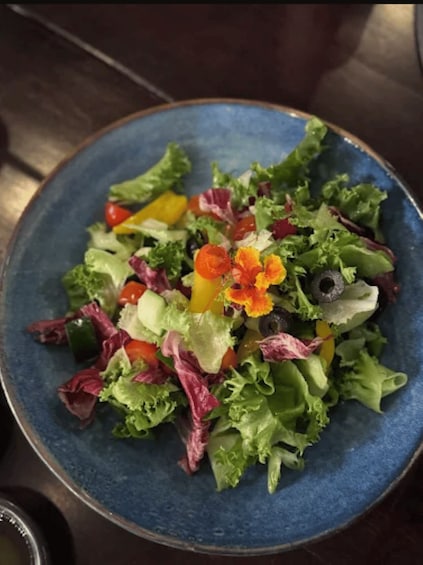 A blue plate with a mixed green salad, including lettuce, tomatoes, and possibly some bell peppers. 5