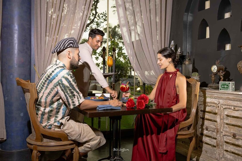 A dining table with a meal, a person serving food, and a decorative setting. 1