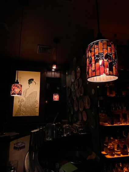 A dimly lit bar with decorative hanging lamps, a wall-mounted plate rack, and a framed artwork. 5
