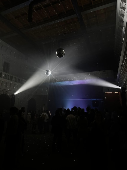 A dimly lit venue with a disco ball and spotlights. 3