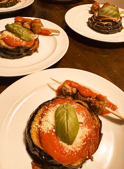 A plate of stuffed eggplants with tomato sauce and a basil leaf garnish. 5