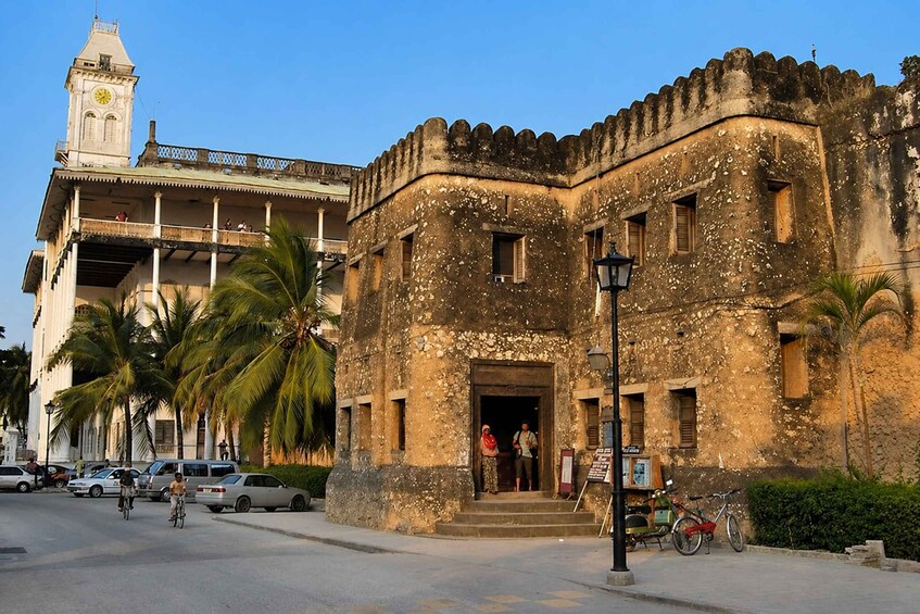 A historic building with a clock tower, palm trees, and parked bicycles. 2