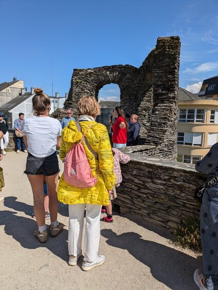 A group of people standing at the ruins of an ancient stone structure. 4