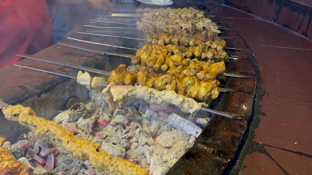 A variety of meats being grilled on skewers over an open flame. 2