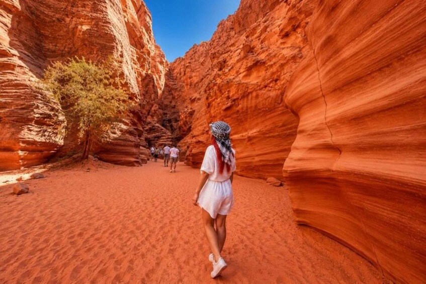 A person walking through a red rock canyon with a clear sky. 3