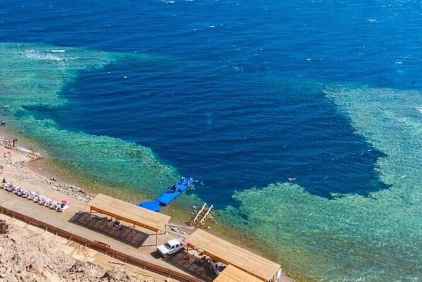 A beach with clear water, a wooden pier, and a boat. 5