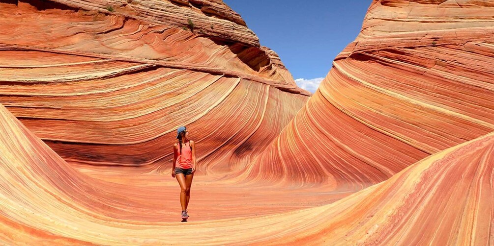 A person standing in a red rock canyon with layered rock formations. 1