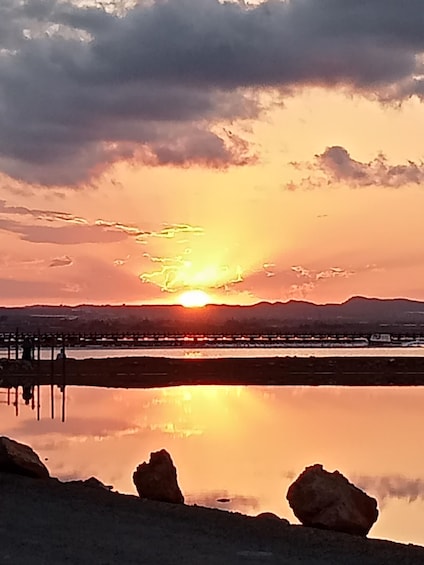 A sunset over a calm lake with mountains in the background and a pier extending into the water. 2