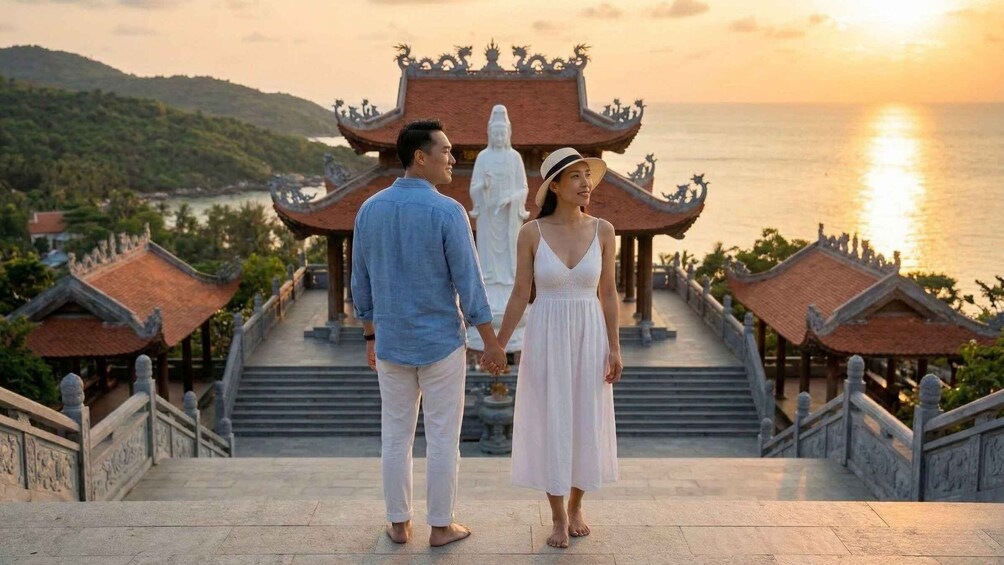 A couple holding hands on a staircase with traditional architecture and a statue in the background. 4