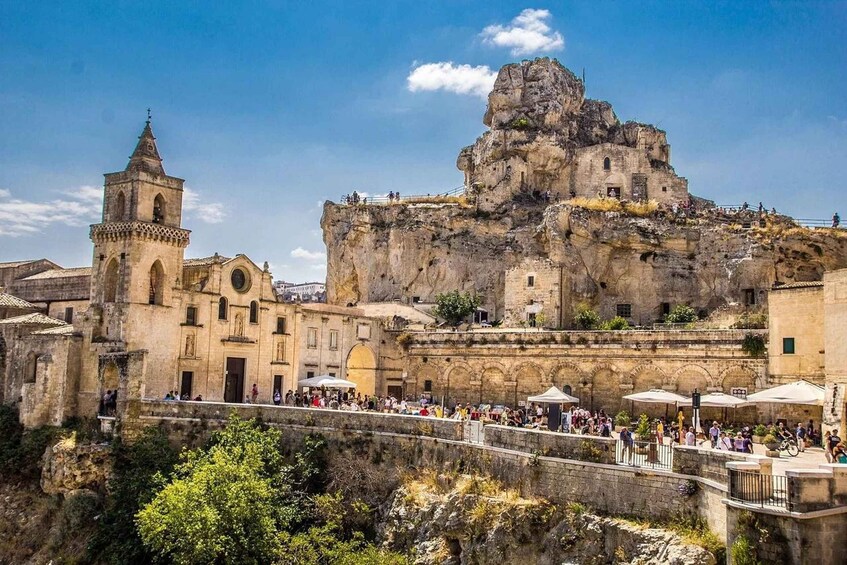 A historic town with a prominent church, a bell tower, and a large rock formation. 2