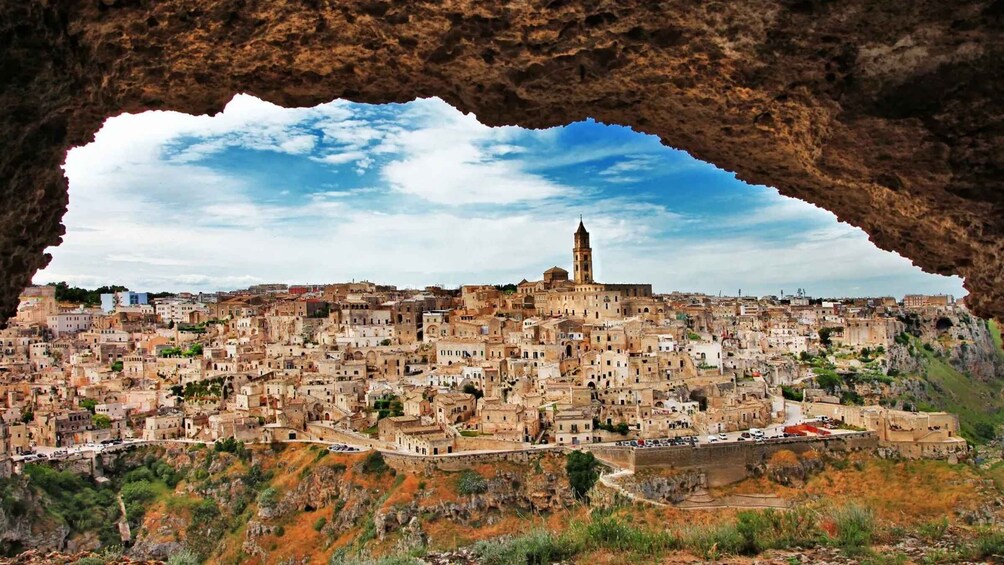 A cityscape viewed through a natural arch, with a prominent tower and densely packed buildings. 1