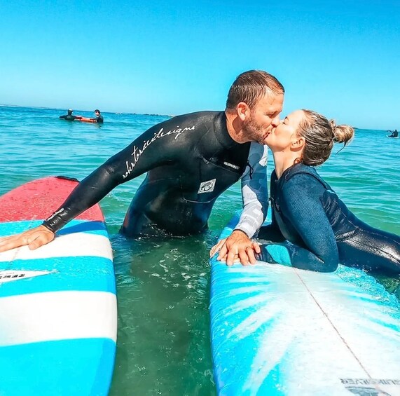 Two people in wetsuits on surfboards in the ocean. 1