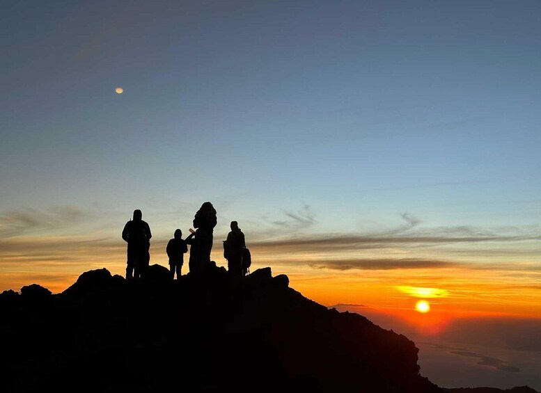 A group of people silhouetted against a sunset on a mountain peak. 5